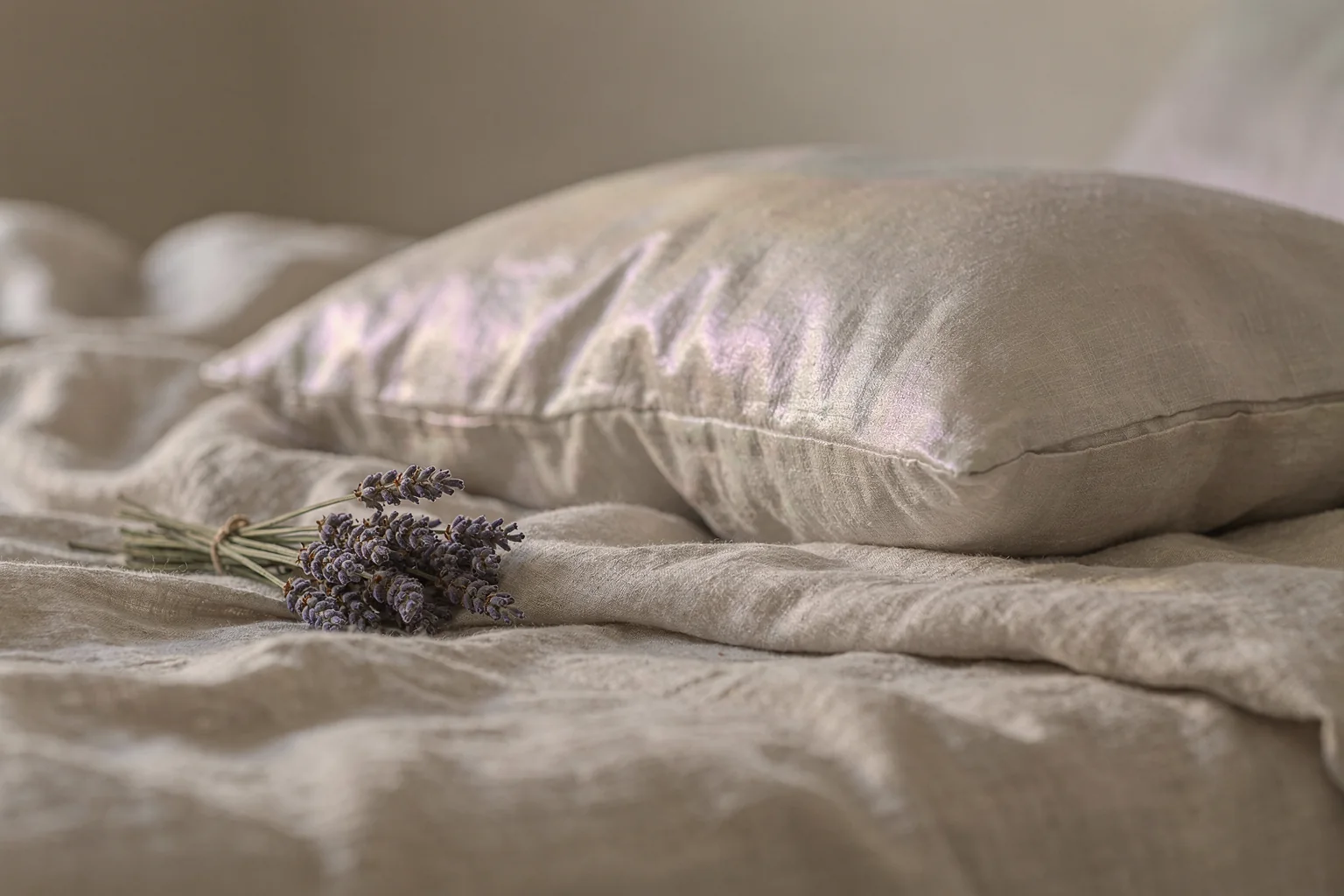 A small bundle of dried lavender resting on soft linen bedding